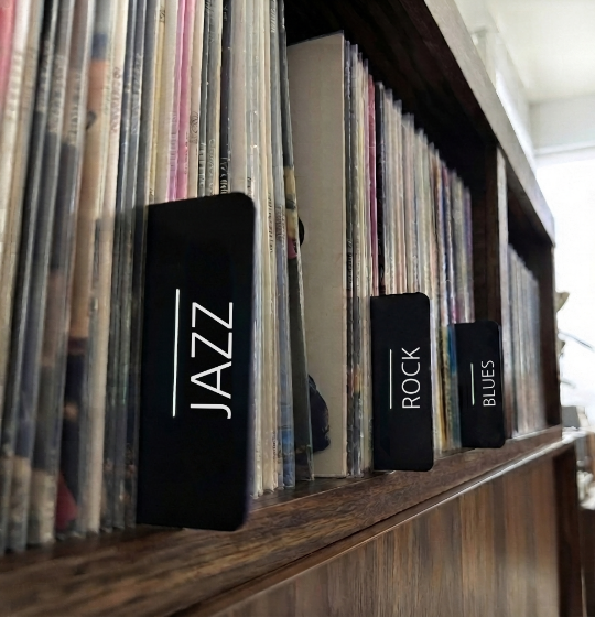Vinyl records organized with black jazz and rock genre dividers on a wooden shelf.