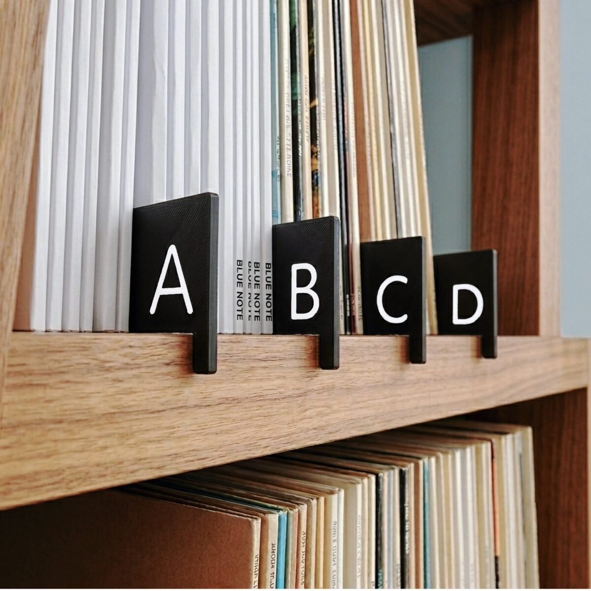 Alphabetical A-Z vinyl record dividers organize vinyl albums on a wooden shelf, and grab onto edge of shelf with a lip feature.