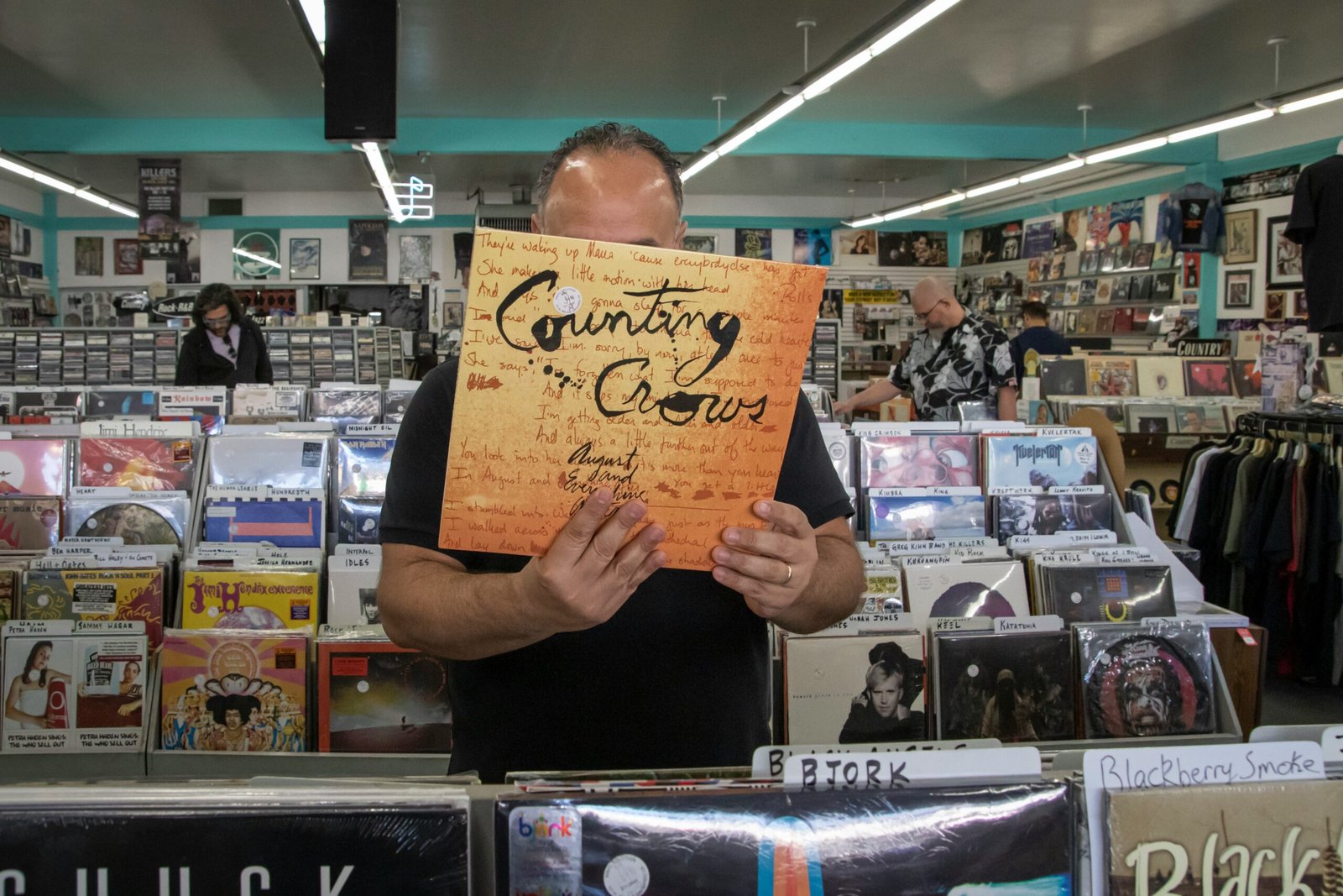 A man holding up a sign inside a California record store during a vinyl hunting trip.
