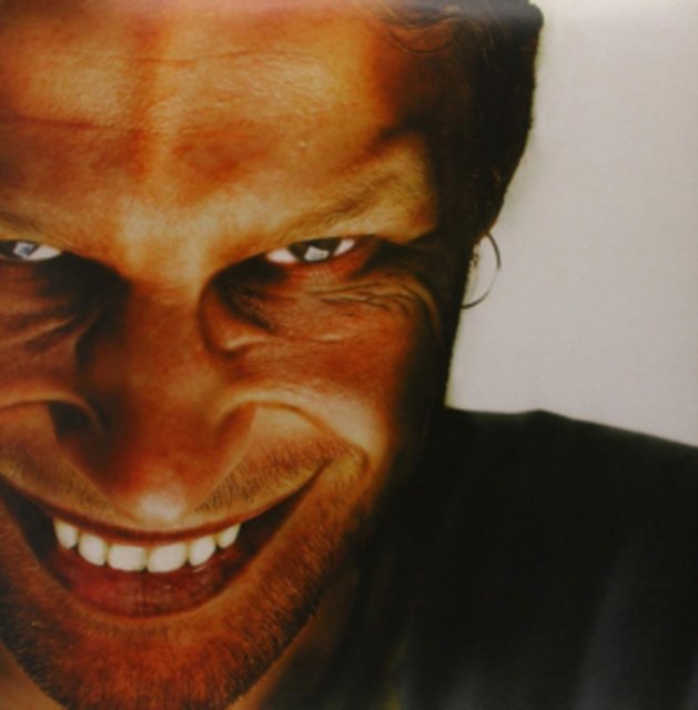 Extreme close-up portrait of a man with a sinister, unnaturally wide grin.