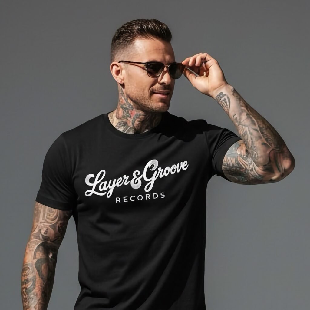 Tattooed man wearing sunglasses and a black Layer & Groove Records graphic t-shirt.