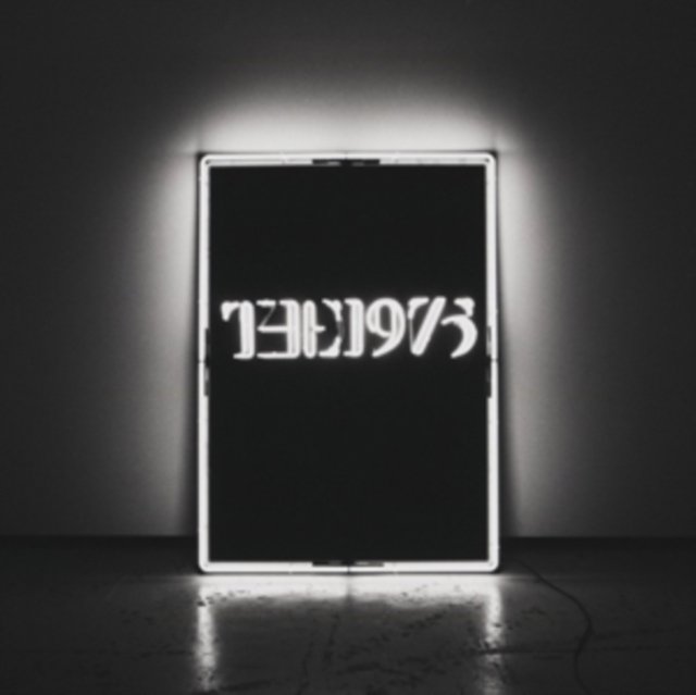 Illuminated neon light box with mirrored The 1975 text in a dark room.