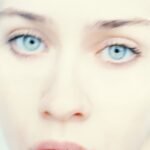 Close-up high-key portrait of a person with striking icy blue eyes and fair skin.