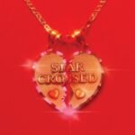 Gold broken heart pendant reading Star Crossed on a vibrant red background.