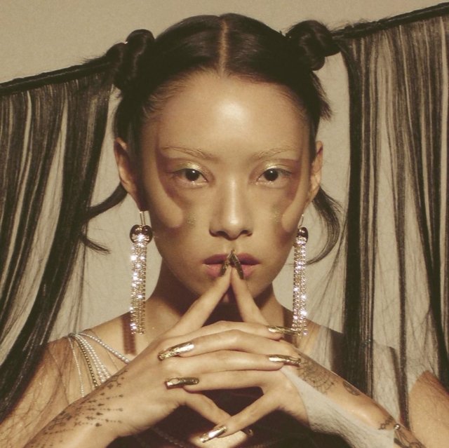 High-fashion futuristic portrait featuring sleek top knots, metallic makeup, and long gold nails.