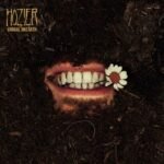 Hoziers Unreal Unearth album cover featuring a mouth buried in soil holding a daisy.