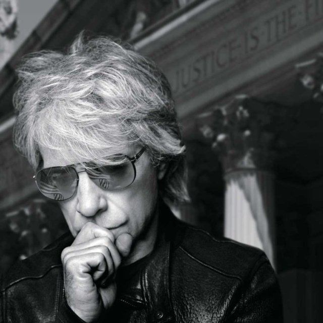 Black and white portrait of Jon Bon Jovi wearing sunglasses and a leather jacket.