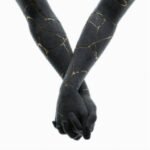 Black kintsugi sculpture of two hands holding each other with gold veins.