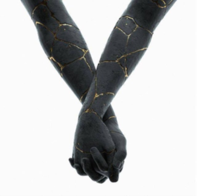 Black kintsugi sculpture of two hands holding each other with gold veins.