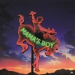 Vintage Mamas Boy neon sign of a cowboy riding a bucking bronco at sunset.