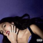 Album cover of Olivia Rodrigos GUTS featuring her wearing silver rings spelling GUTS.