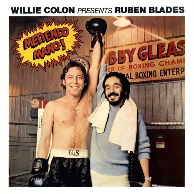 Album cover for Metiendo Mano! featuring Willie Colón and Rubén Blades in a boxing ring.